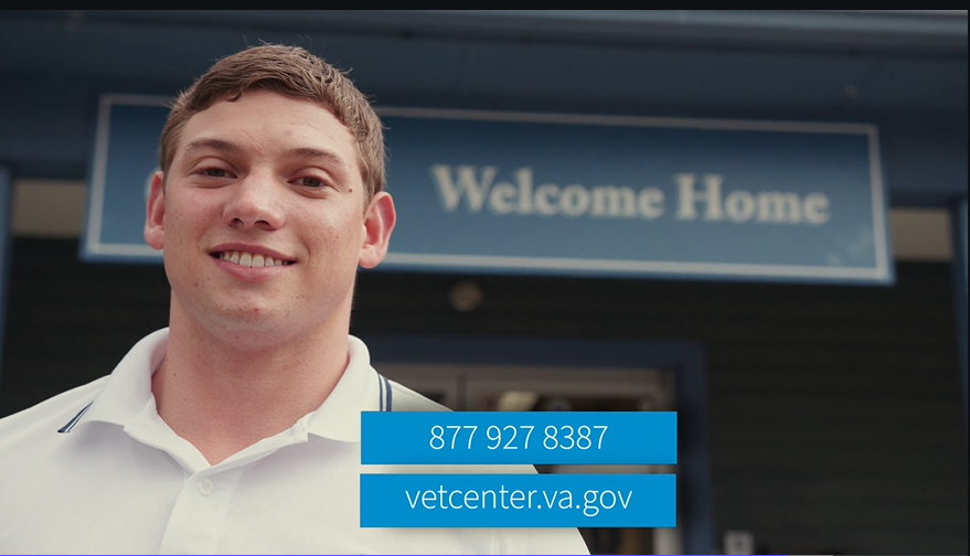 A Veteran smiles while standing in front of a Vet Center